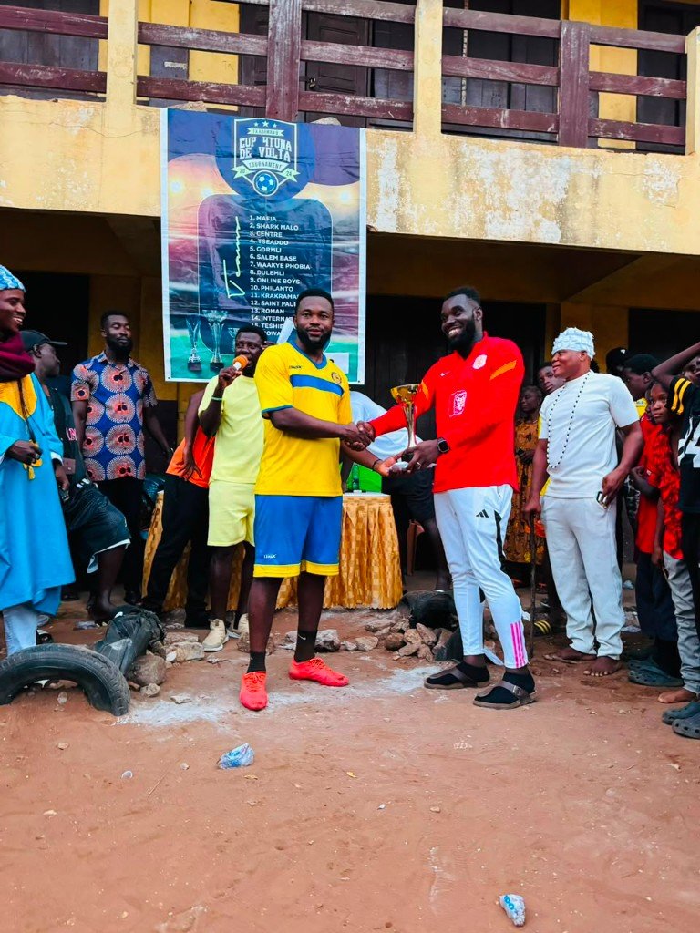 A trophy being presented during a community football gathering