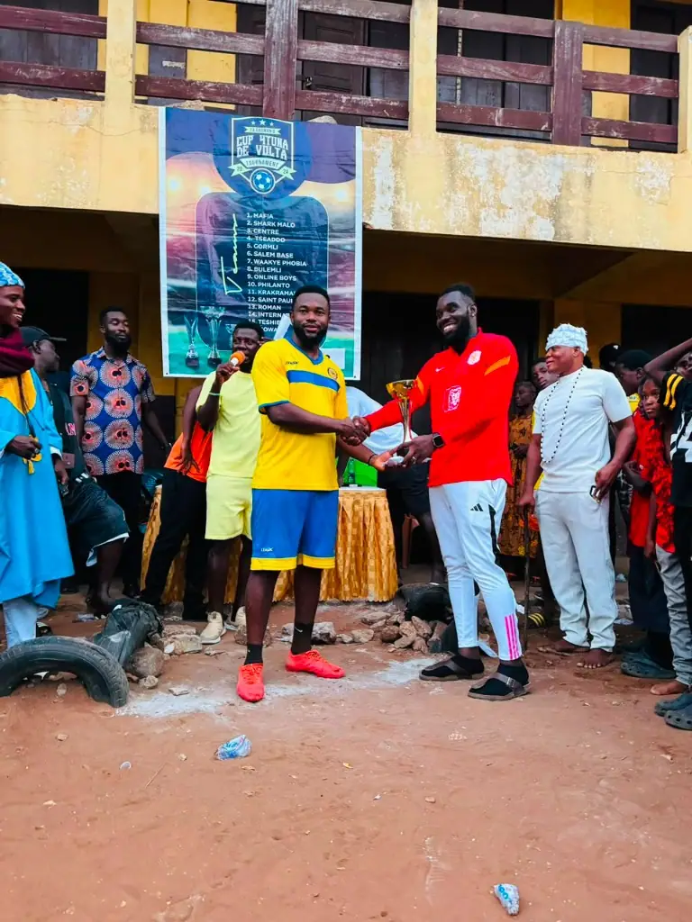 A trophy being presented during a community football gathering
